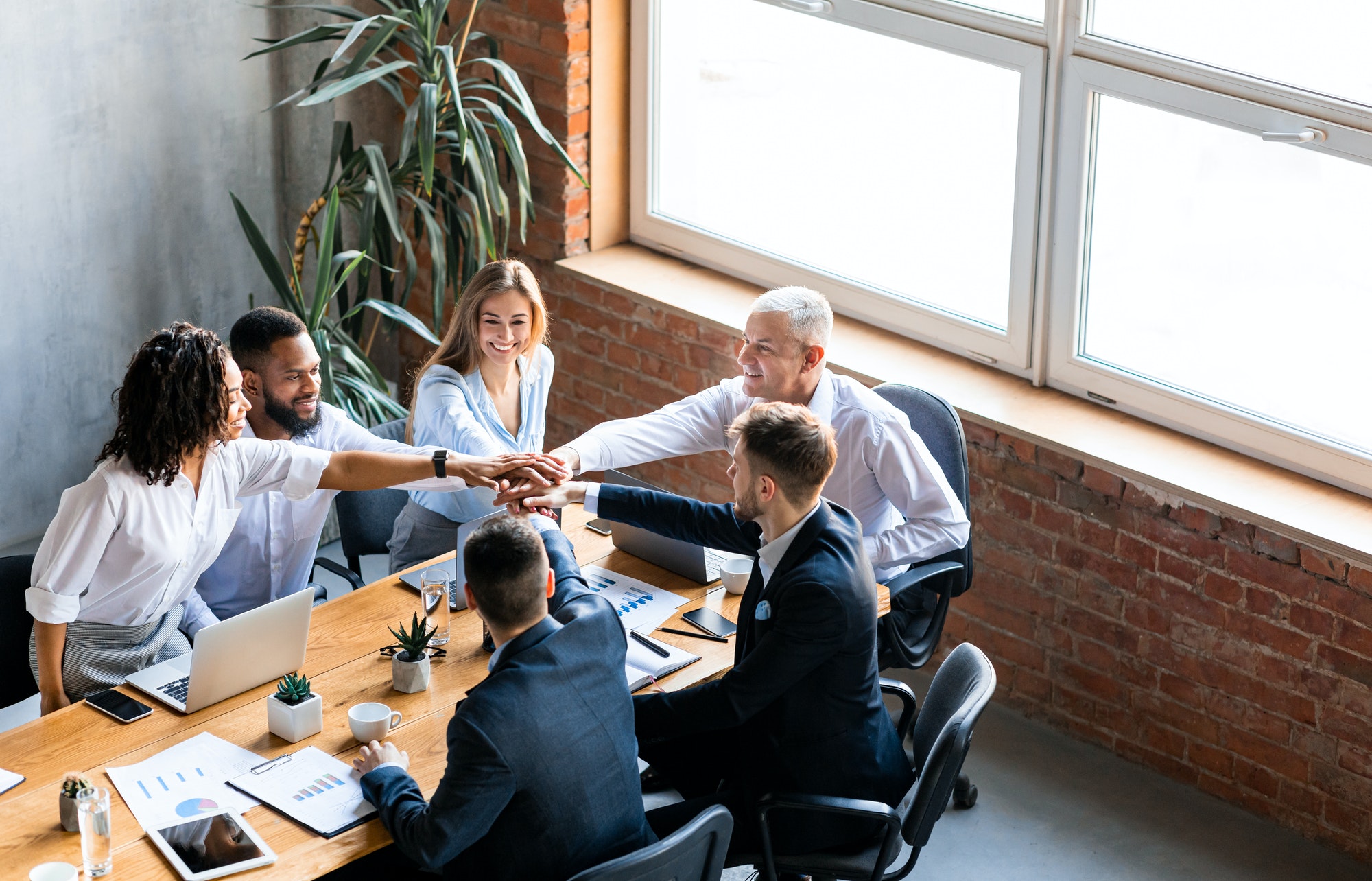 United Business Team Holding Hands Sitting Together In Modern Office